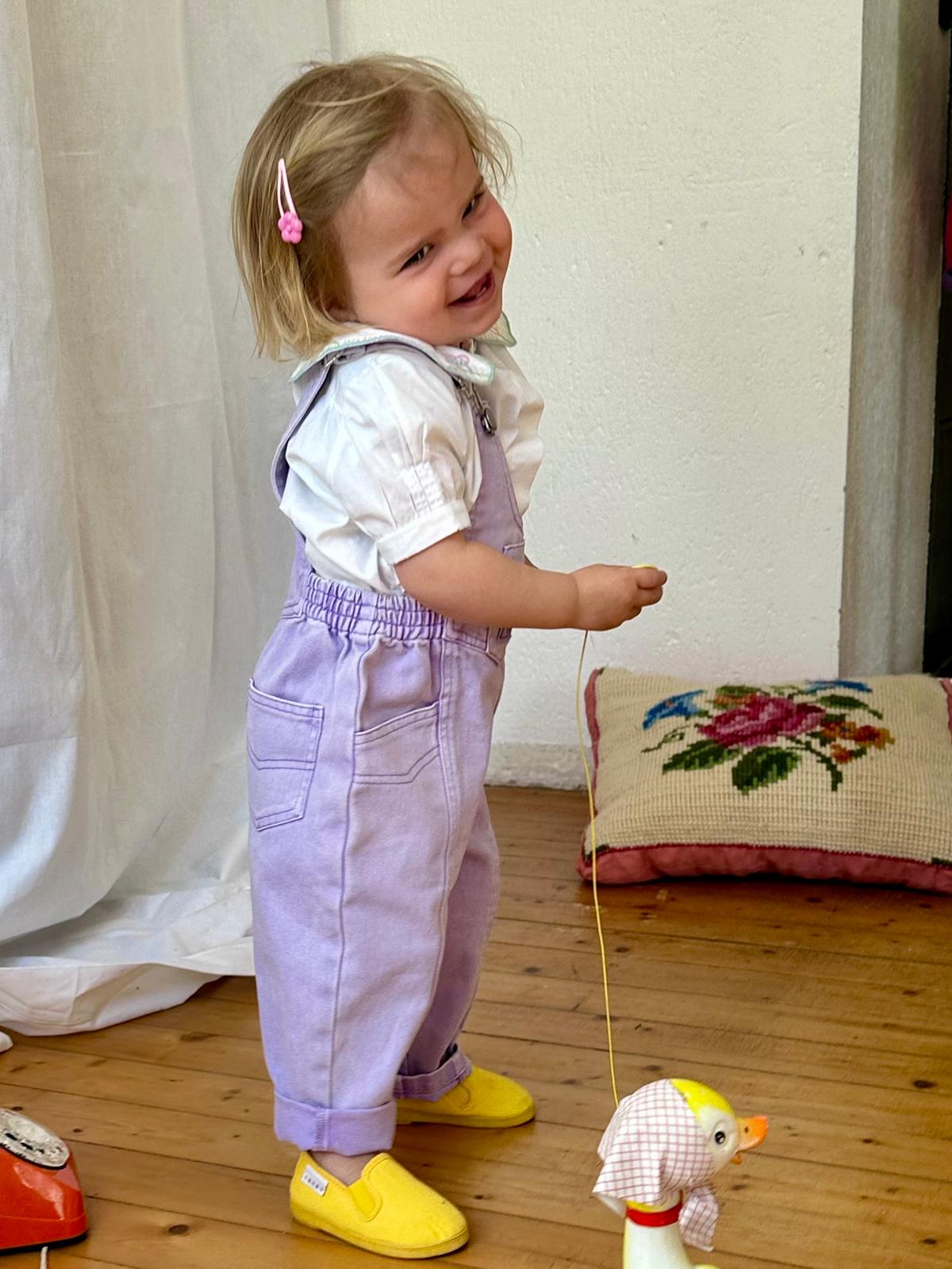 Enfant coquin 2 ans de profil en salopette mauve vintage