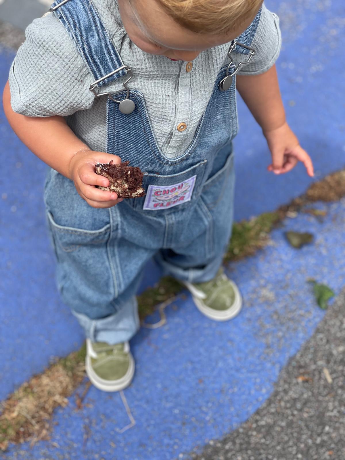 Contre plongée sur enfant 2 ans en salopette bleu jean vintage