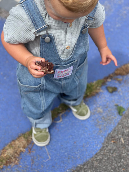 Contre plongée sur enfant 2 ans en salopette bleu jean vintage