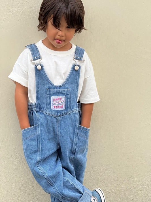 Salopette enfant en jean bleu avec étiquette tissée,mains dans les poches