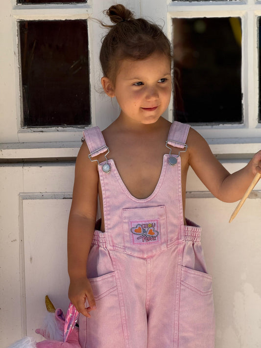 Fille  3 ans en salopette rose à l'exterieur