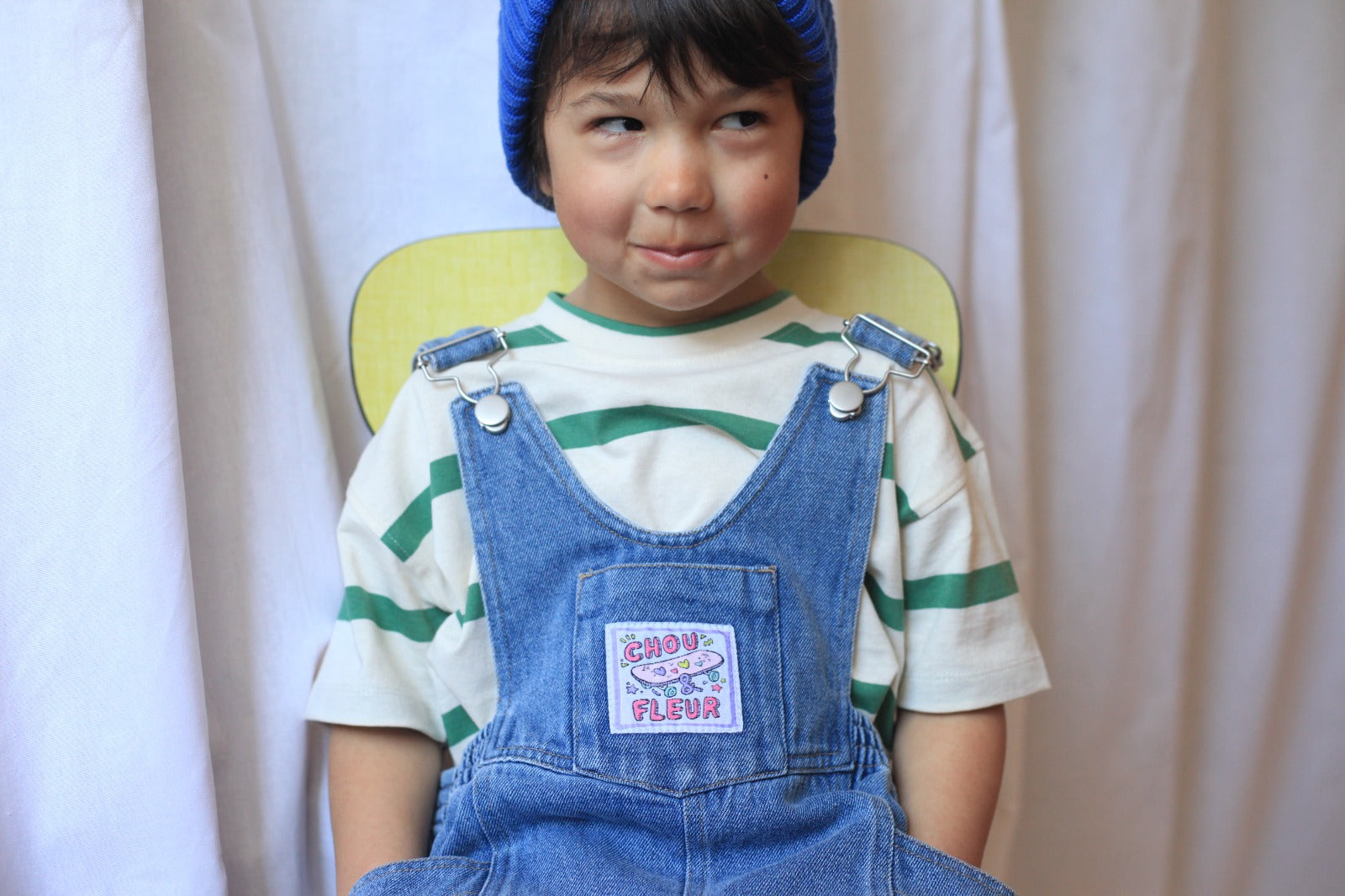 Salopette en denim bleu pour enfant, look vintage avec bonnet tricoté et t-shirt rayé vert