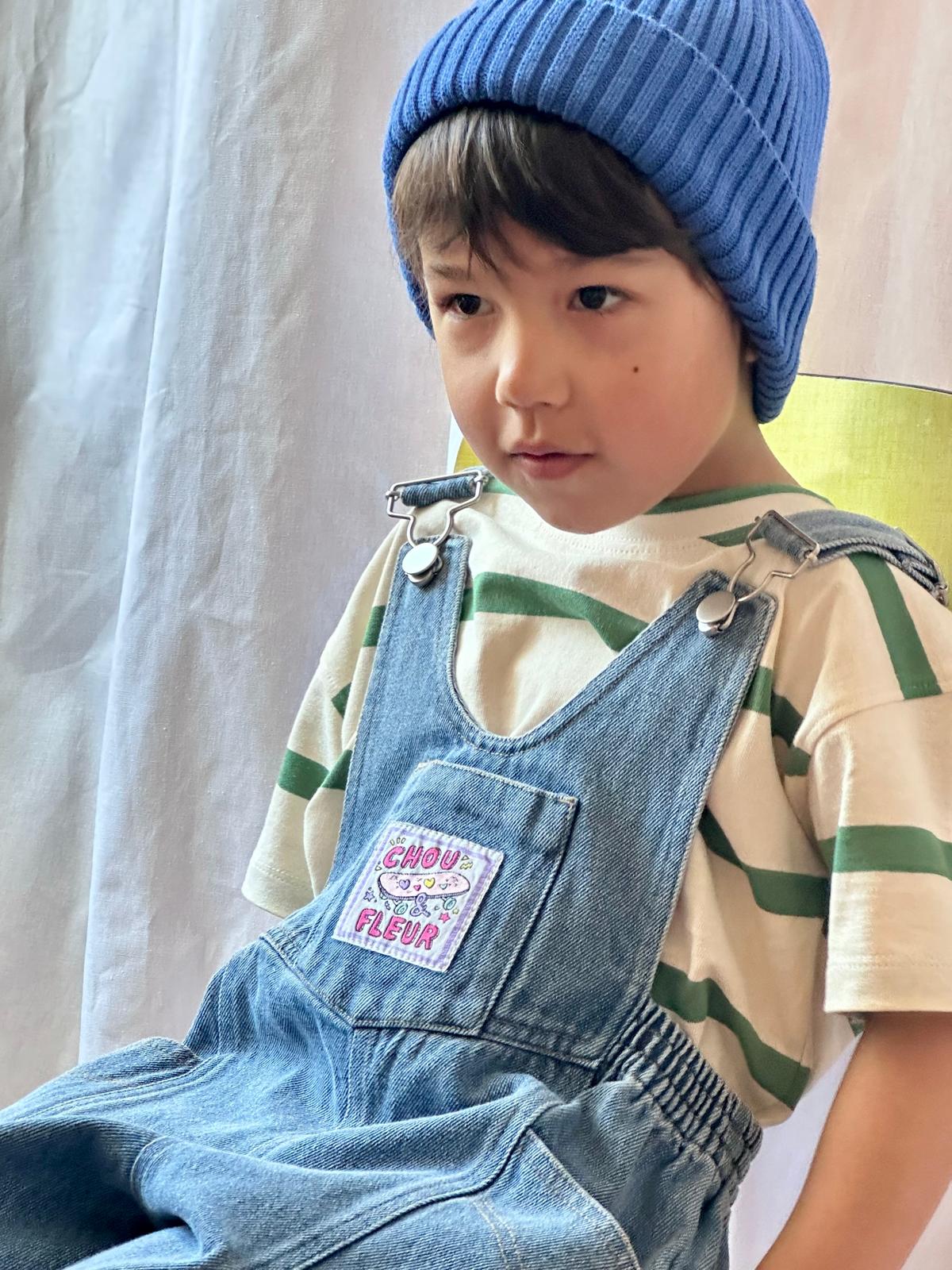 Gros plan sur les bretelles d’une salopette en denim pour enfant — détail couture et qualité.