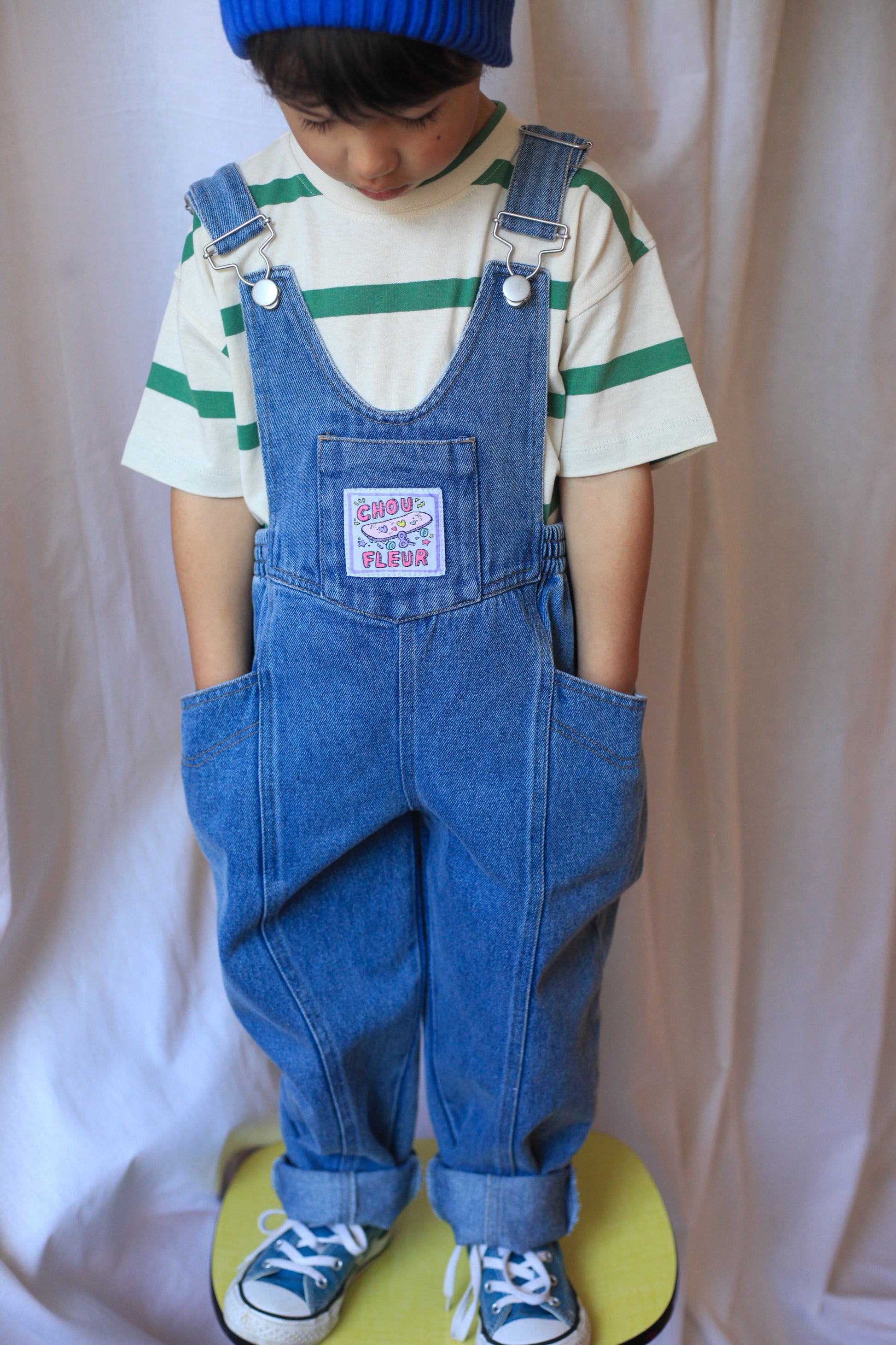 Salopette enfant en jean bleu avec étiquette tissée, tenue tendance et confortable.