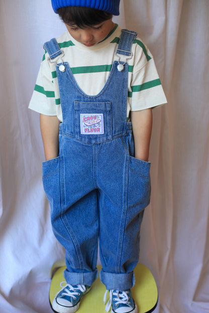 Salopette enfant en jean bleu avec étiquette tissée, tenue tendance et confortable.