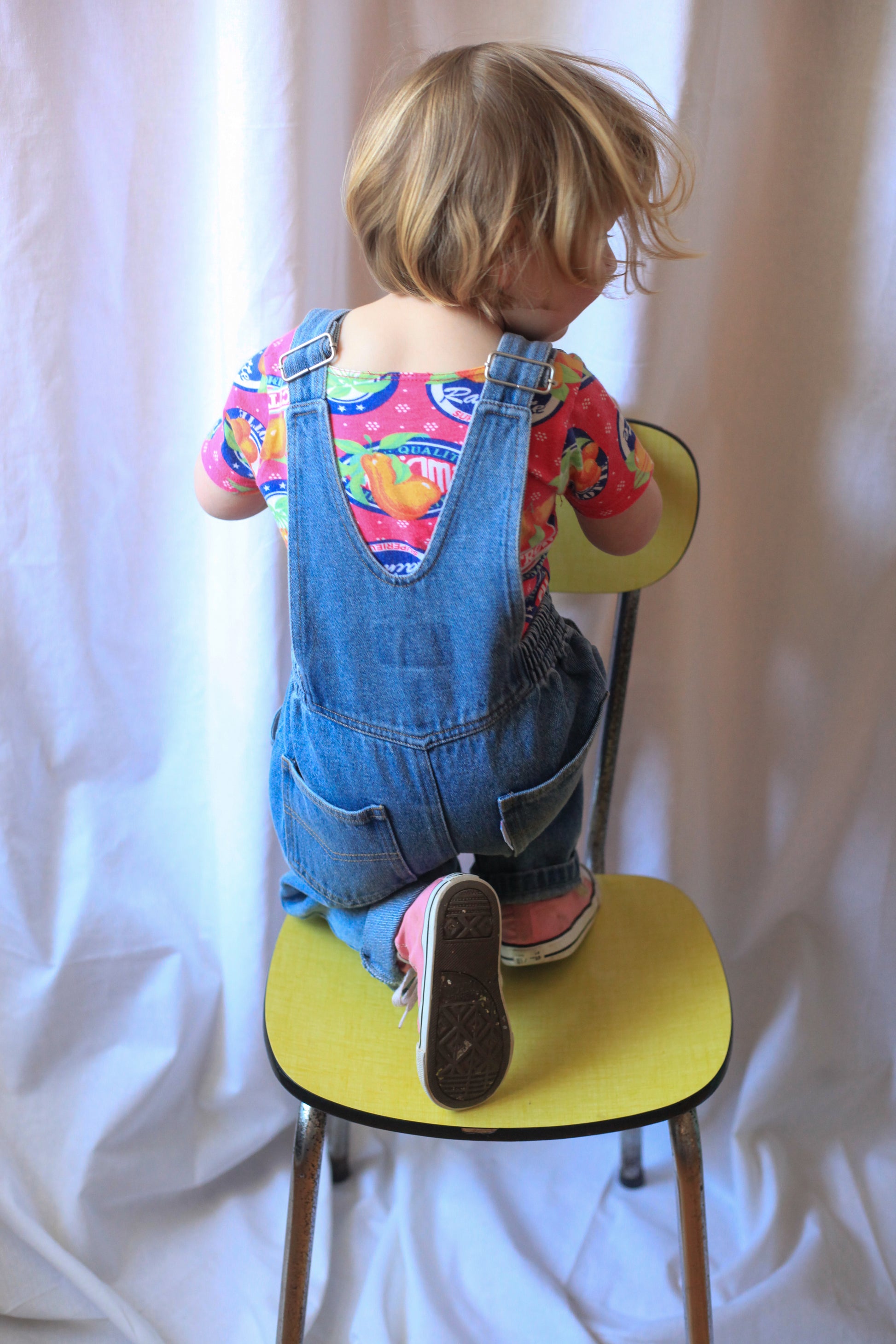 Vue de dos d’une enfant en salopette denim bleu vêtement enfant au style rétro moderne