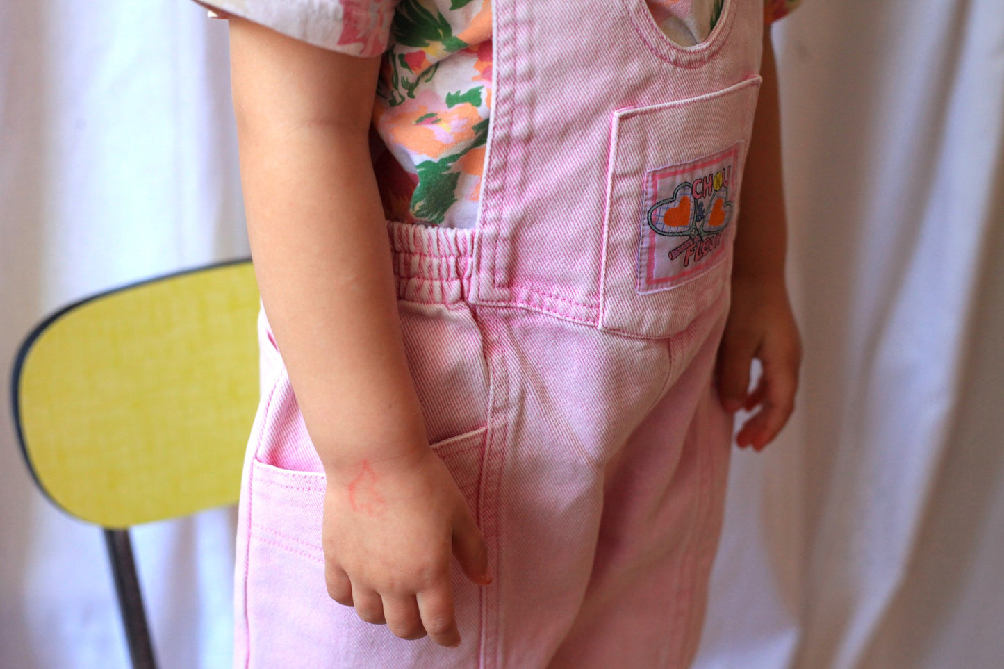 Zoom sur la salopette rose vintage pour enfant avec étiquette tissée 'Chou et Fleur' sur la poche avant