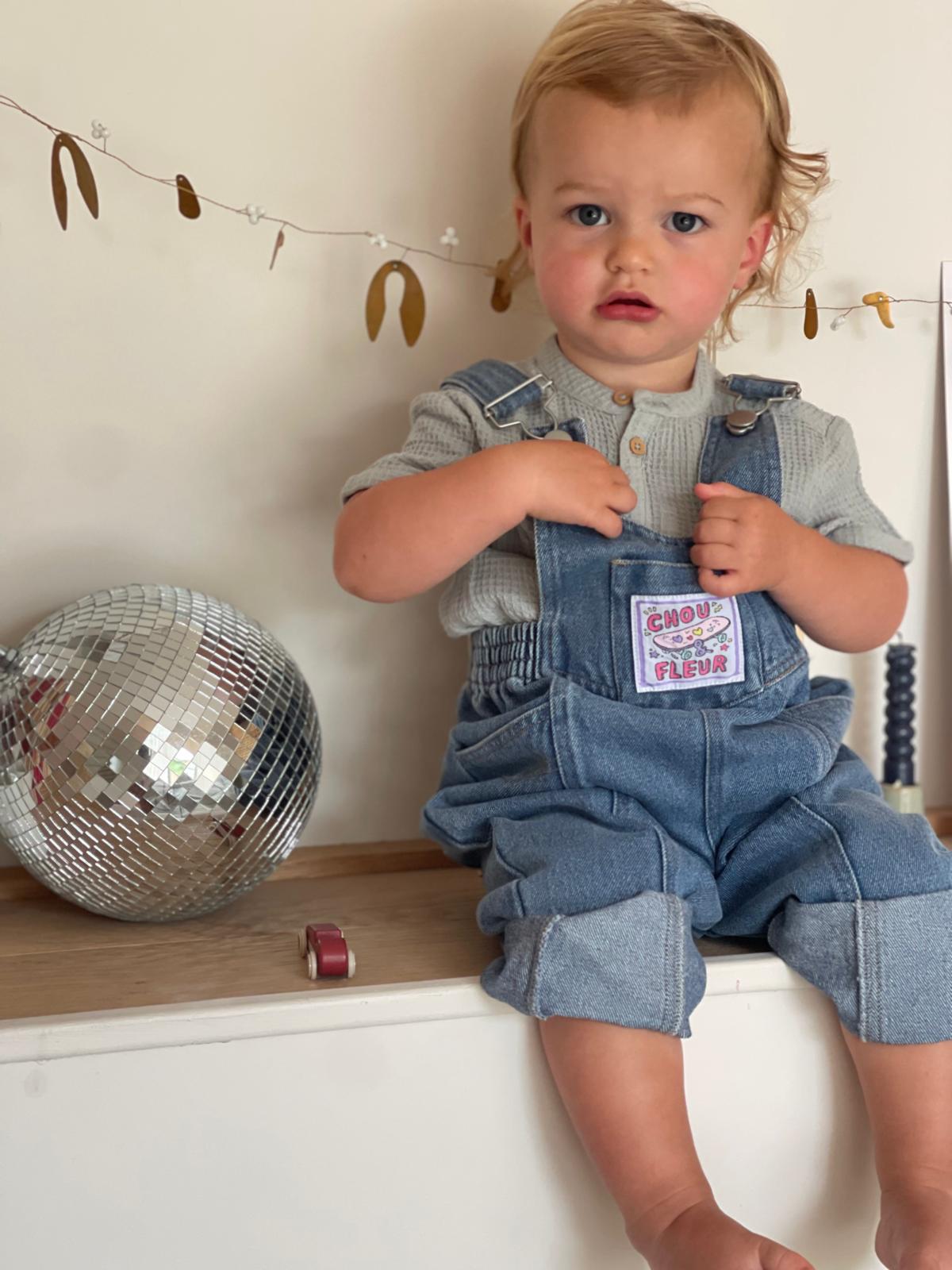 Garçon de 2 ans en salopette jean vintage, position assise
