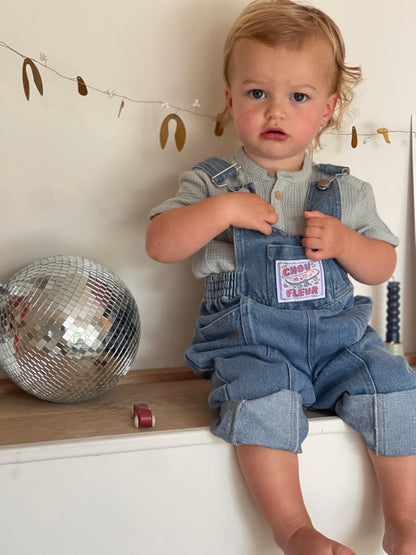 Garçon de 2 ans en salopette jean vintage, position assise